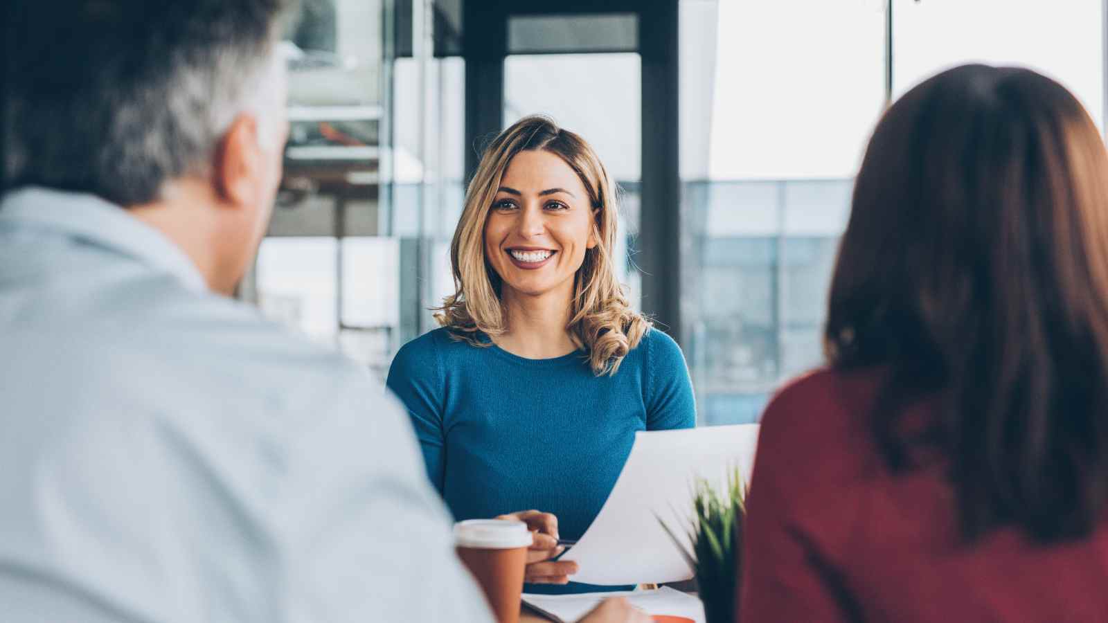 Woman holding paper in a meeting with two other people