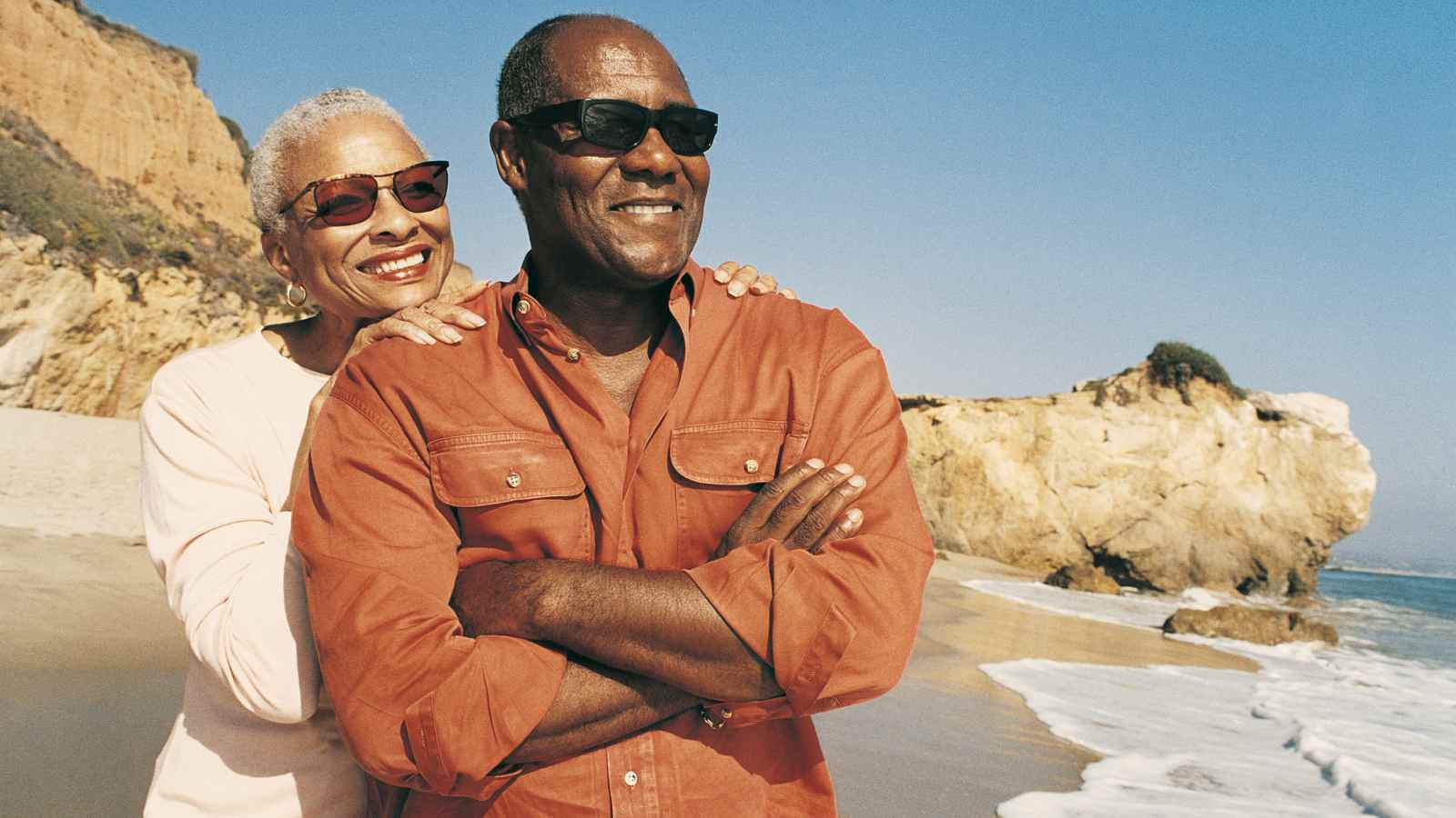 Older couple on the beach with sunglasses looking out to water